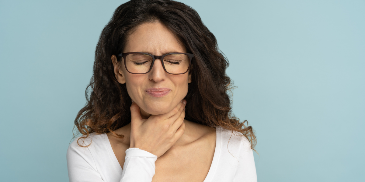 Frau, die heiser ist uns sich den Hals hält.