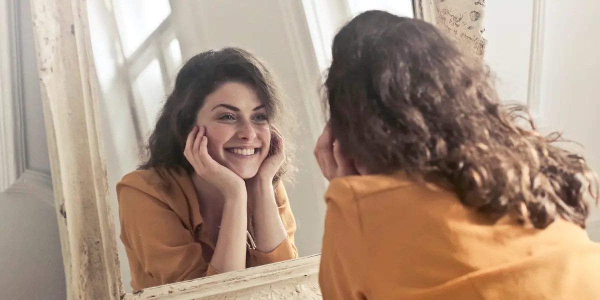 Authentische junge Frau, die sich im Spiegel betrachtet